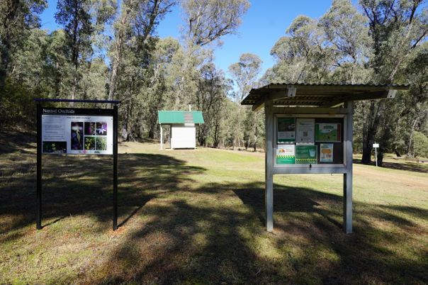 Signs and toilet in grassy clearing