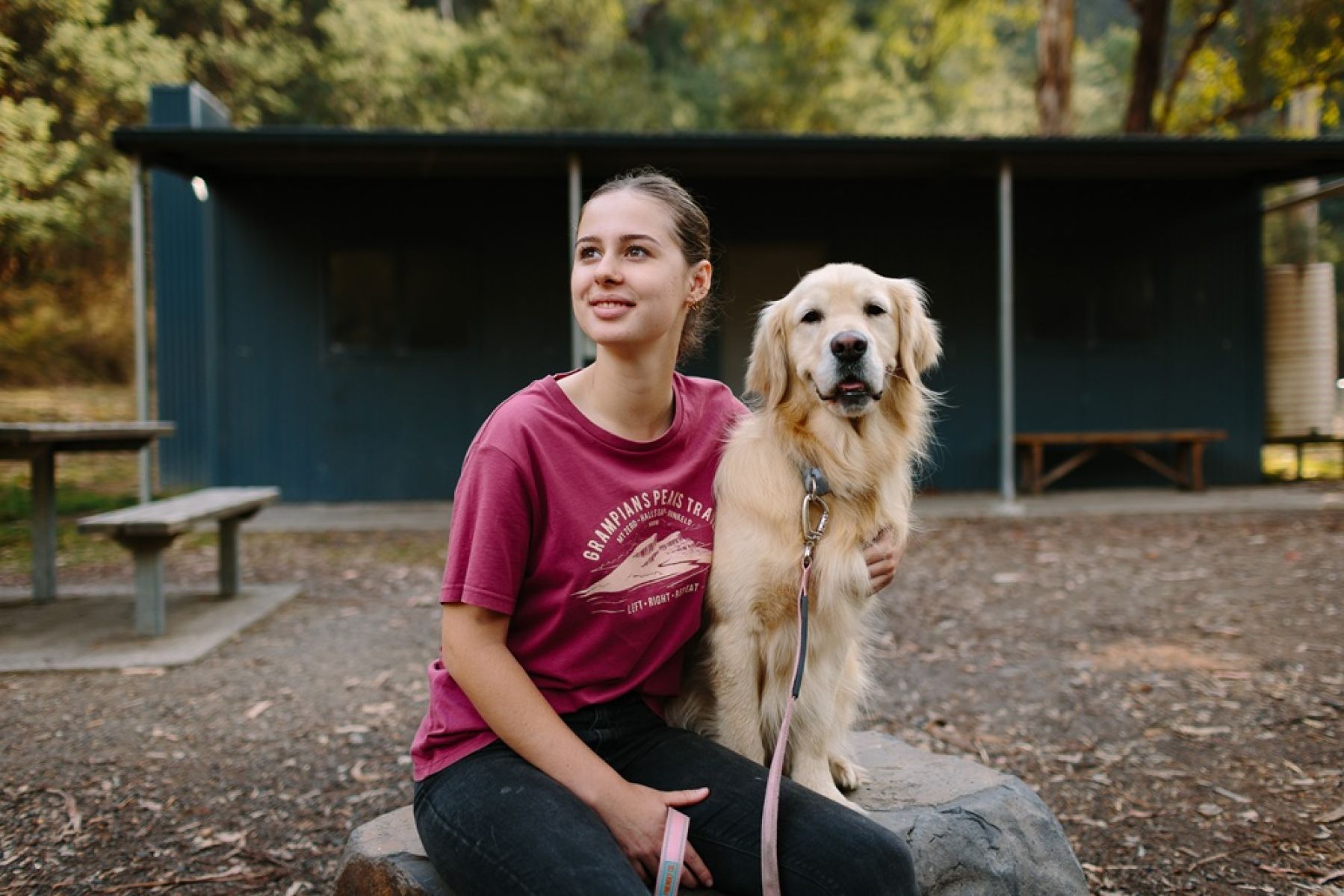 A person and golden retriever dog in front of a hut