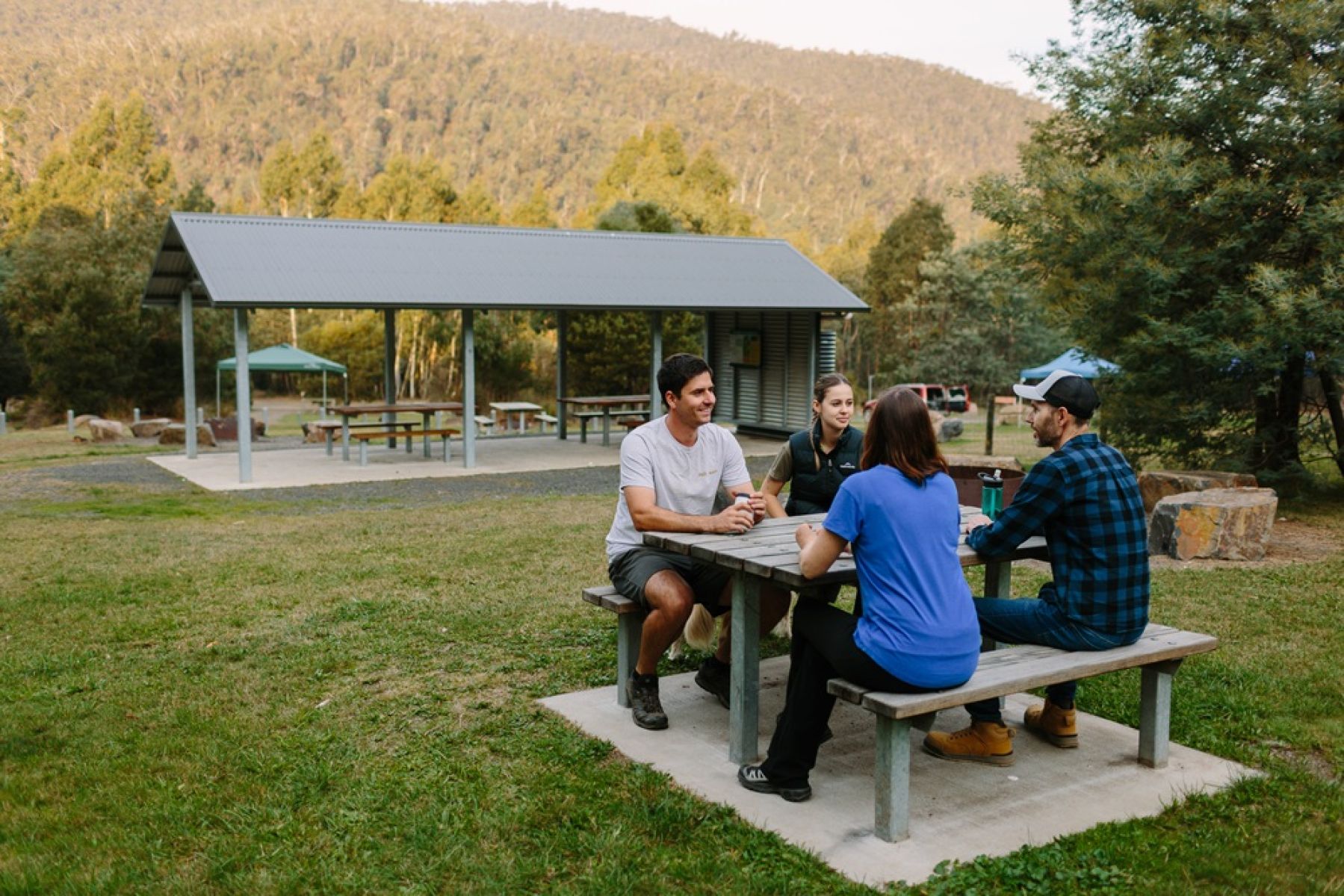 Group of people sitting at a table, with a large picnic shelter in the background
