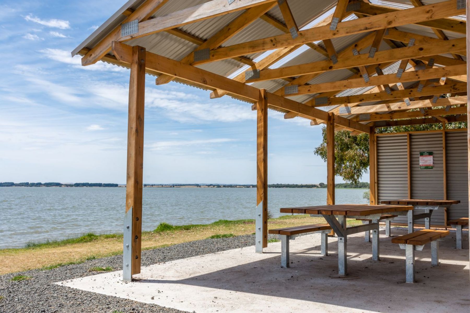 A picnic shelter looking over a lake on a sunny day.