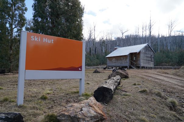 A sign in foreground with wooden hut in background