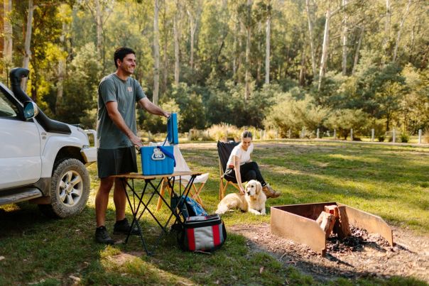 Two people beside a firepit and 4WD vehicle